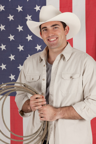 Cowboy with lasso standing in front of an american flag