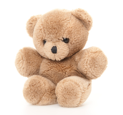 A pretty Teddy Bear brown with blond hair and a blue dress sits on a white background