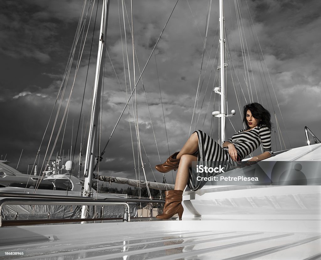 Moda hermosa modelo posando en yate de lujo bajo cielo melancólico - Foto de stock de Anticuado libre de derechos