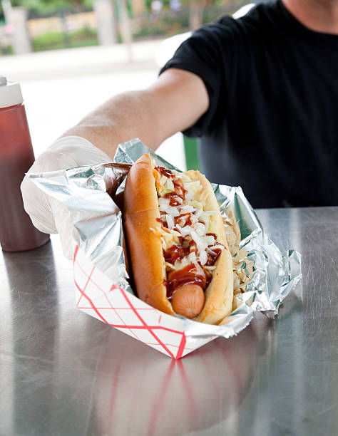 Hotdog Preparation "A hotdog is prepared at a hotdog stand.  Series, 3 of 3." hot dog stand stock pictures, royalty-free photos & images