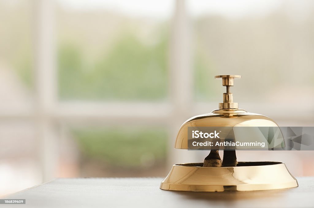 Латунная Звонок портье, сидящая на стойке регистрации у окна - Стоковые фото Антиквариат роялти-фри