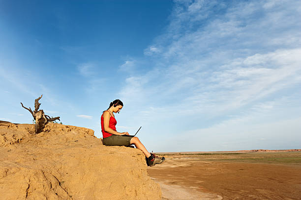 A young girl works with a laptop on the mountain overlooking the rainforest and the beach. Work and travel.