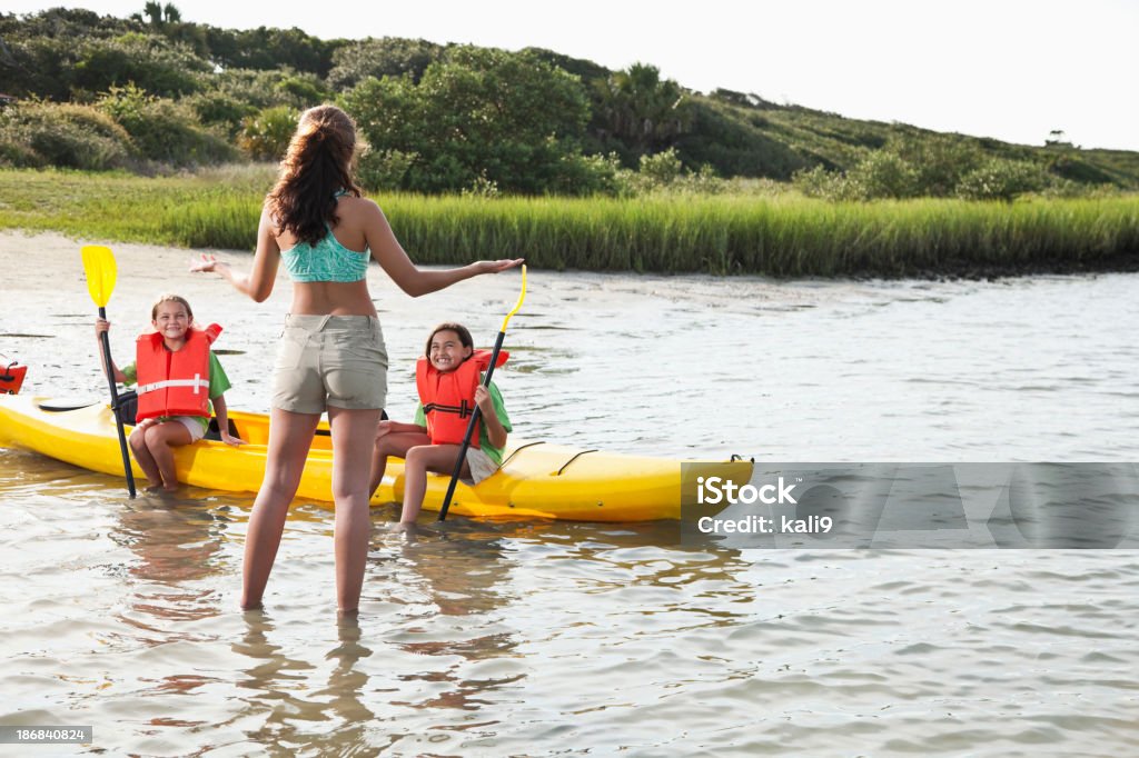 Adolescent avec petites filles assis sur un kayak - Photo de Animateur de colonie de vacances libre de droits