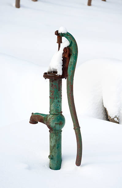 Antique water pump in the snow An antique water pump buried outdoors after a heavy snow. old fashioned well hand pump stock pictures, royalty-free photos & images
