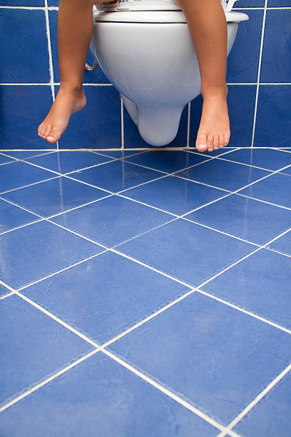 istock Child sitting on a toilet in a blue tiled bathroom 186841129