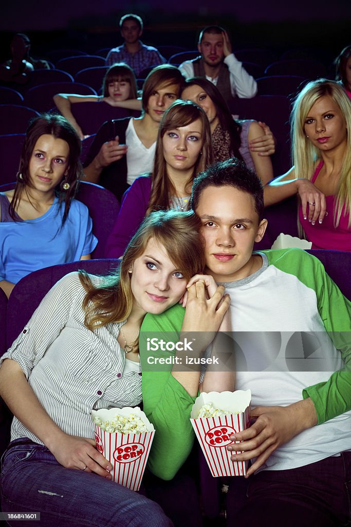 Date in movie theater Young adult couples sitting in the cinema and watching romantic movie. They holding hands and cuddle to each other. Movie Theater Stock Photo