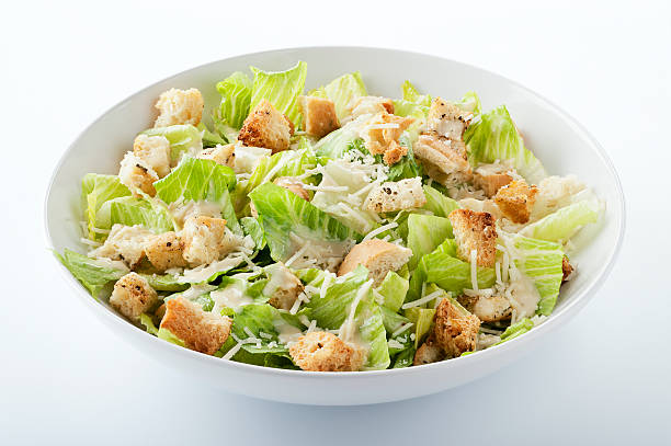 Caesar Salad "SEVERAL MORE IN THIS SERIES. Closeup of a fresh caesar salad, with romaine lettuce hearts, croutons, parmesan cheese and dressing.  Isolated on white with clipping path.NB:  Clipping path might be available only for the largest size.  If the clipping path is important to you, please contact iStockphoto Support to find out their current policy for image sizes that include clipping paths." augustus caesar photos stock pictures, royalty-free photos & images