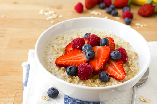 A bowl of healthy porridge with fresh berries and drizzled with honey.