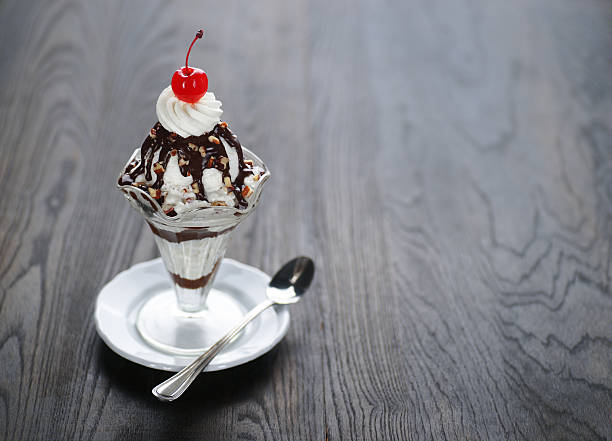 Hot Fudge Sundae "Iconic, classic, hot fudge sundae with whipped cream, nuts, and a cherry.  Oriented horizontally with plenty of text space." parfait photos stock pictures, royalty-free photos & images