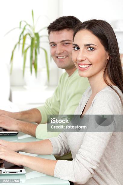 Two Young Students Working On Laptop Computer Stock Photo - Download Image Now - Adult, Adults Only, Brown Hair