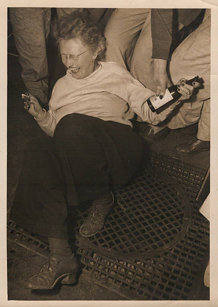 Archival Photo Too Much An archival photo from the late 1930's or early 1940's of a middle aged woman in a bar falling down after having too much to drink, a beer in one hand and a cigarette in the other. drunk photos stock pictures, royalty-free photos & images