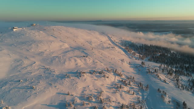 Aerial view overlooking the sunlit slopes of Levi, winter evening in Lapland
