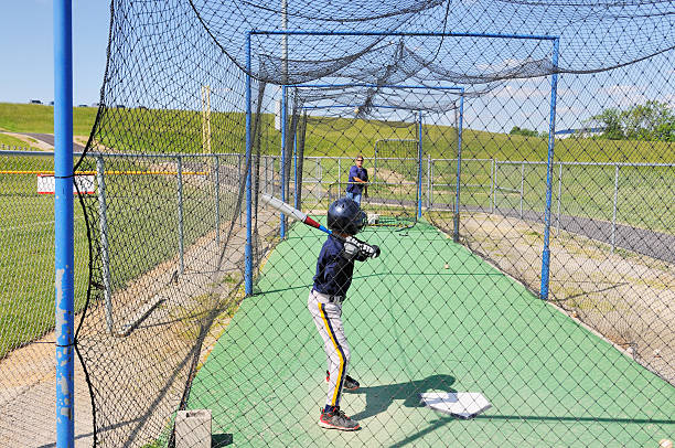 Baseball Player Son in Batting Cage with Coach Father Pitching  baseball cage stock pictures, royalty-free photos & images