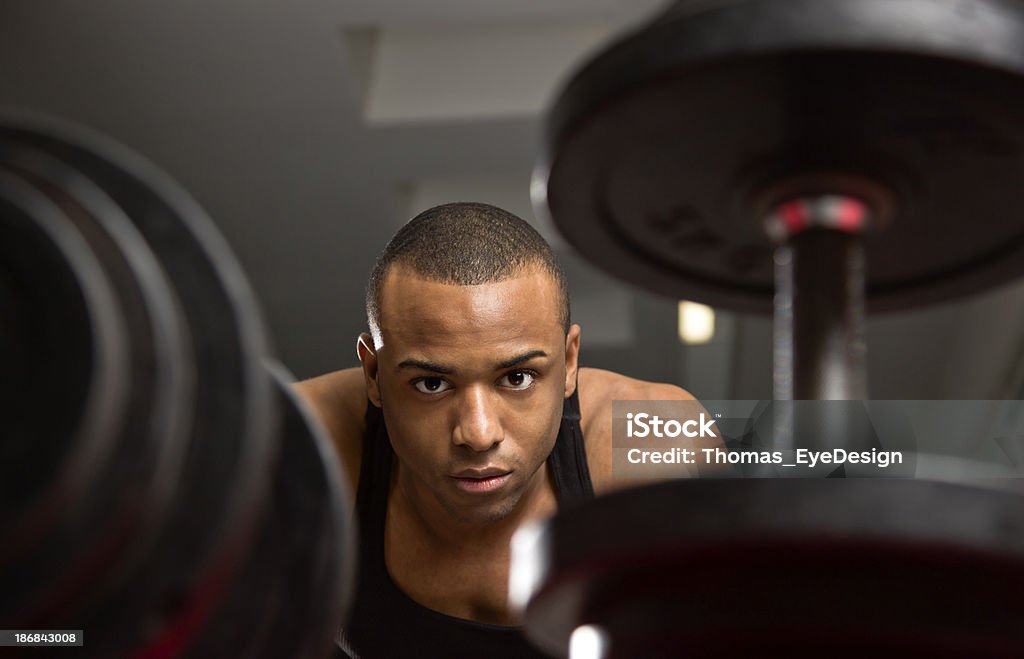 Young Man Looking at Dumbbells Young black male working out in a fitness center. 20-24 Years Stock Photo