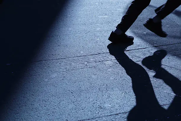 Photo of Lone man running away in blue night shadows