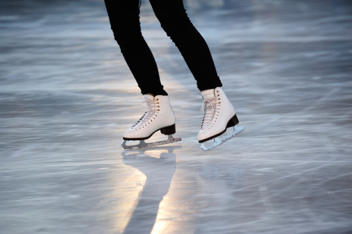 Gild with white skates on ice.