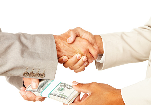 Close-up of a business people handshaking and bribing against white background