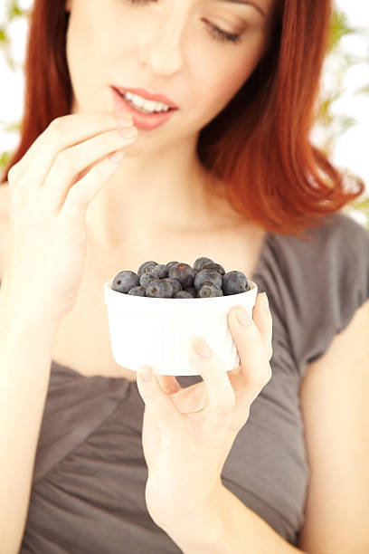 istock Beautiful female eating blueberries from a bowl 186845019