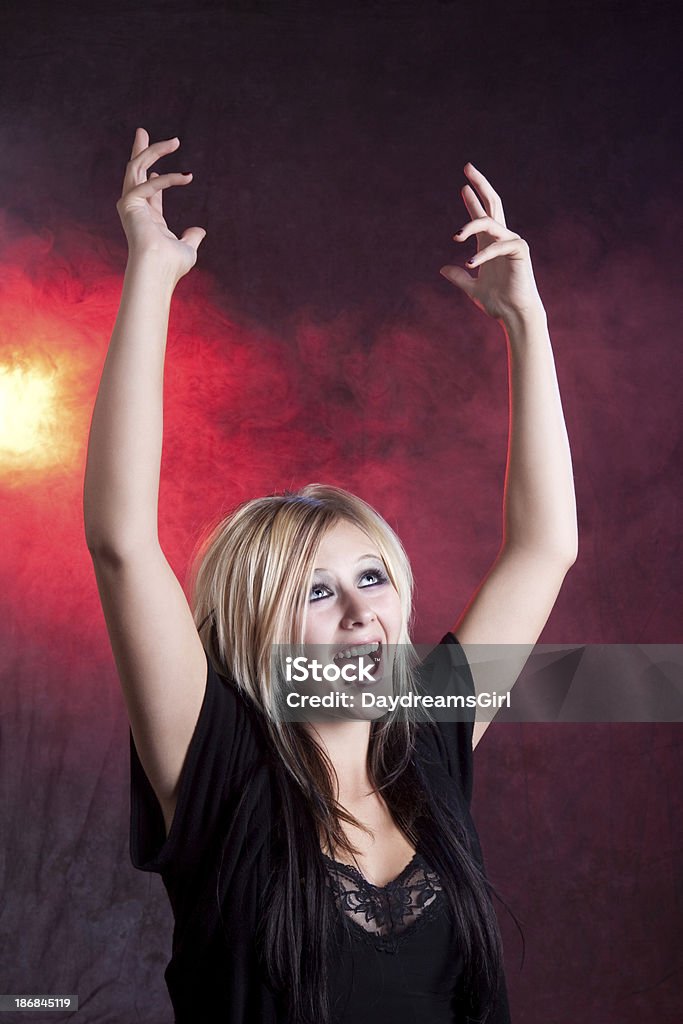 Gothic Teenage Girl with Arms Raised and Screaming "Beautiful teenage girl wearing gothic clothing and make-up, pierced lip, with hands raised and screaming." Reaching Stock Photo