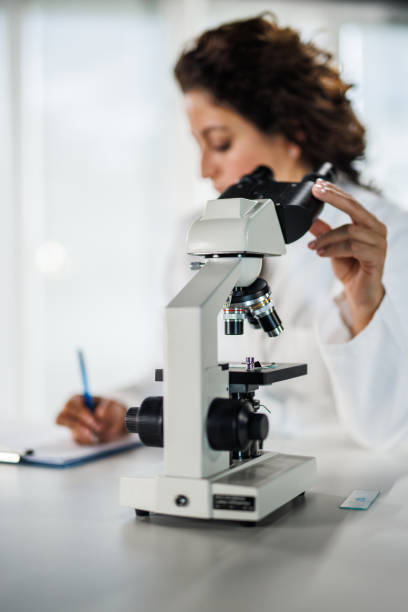 istock Lab tech writing her findings on a clipboard after looking through the microscope and analyzing samples 1868452137