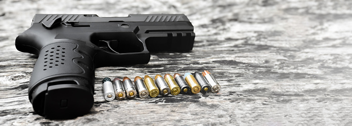 9mm pistol gun and bullets on wooden plank, soft focus.