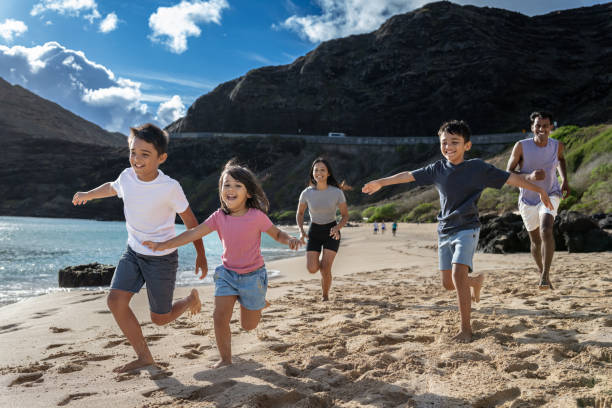 istock Three siblings running on beach with their playful parents 1868454807