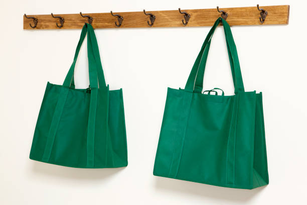 Hand holding little packet green recycle paper bag, isolated on white background