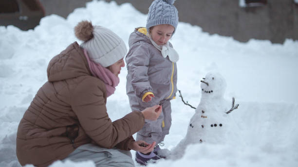istock Family Fun in First Snow. Mom and Kid Making Snowman 1868456391