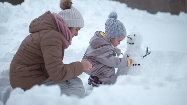istock Family Fun in First Snow. Mom and Kid Making Snowman 1868456395