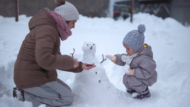 istock Family Fun in First Snow. Mom and Kid Making Snowman 1868456400