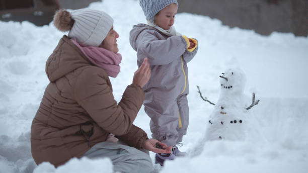 istock Family Fun in First Snow. Mom and Kid Making Snowman 1868456401