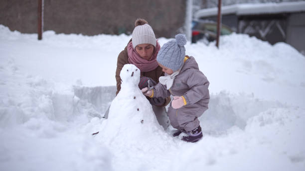 istock Making My First Snowman. Child with Mother Outdoors in Winter 1868456402