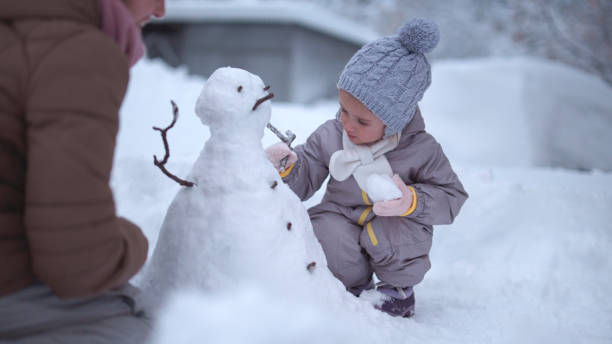 istock Family Fun in First Snow. Mom and Kid Making Snowman 1868456917