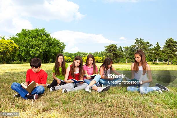 Grupo De Niños Leyendo Libros Al Aire Libre Foto de stock y más banco de imágenes de Campo - Tierra cultivada - Campo - Tierra cultivada, Grupo de personas, Leer