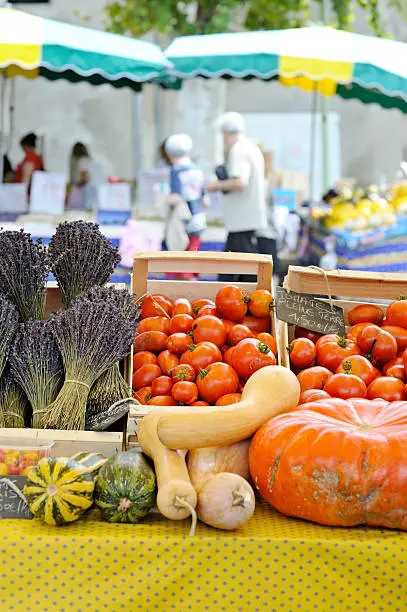 "Tomatoes, pumpikns on French market stall, with traditional Provencal yellow fabric lining stall.More like this"