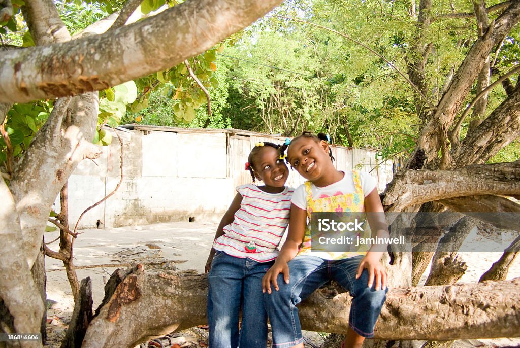 Niñas feliz sentado en el árbol al aire libre y sonriente posando - Foto de stock de Bahamas libre de derechos