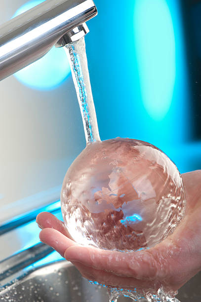 hand halten glas globe auf dem wasser laufen küche wasserhahn. - handful motion blurred motion wet stock-fotos und bilder