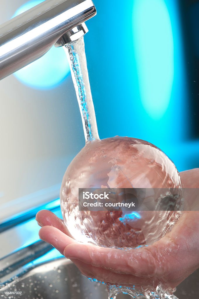 Ręka trzyma Szkło globe w kuchni wodą z kranu. - Zbiór zdjęć royalty-free (Bateria - Wyposażenie)