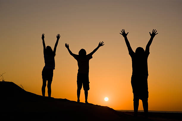 istock Three people enjoying the sunset while raising arms 186847361