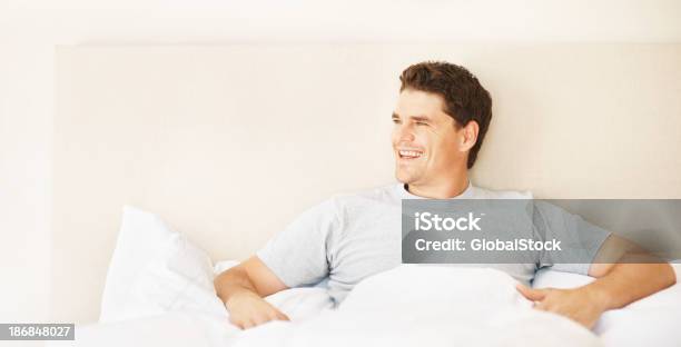 Foto de Smart Mid Adulto Homem Sentado Na Cama Sorrindo e mais fotos de stock de 30 Anos - 30 Anos, 30-34 Anos, Aconchegante