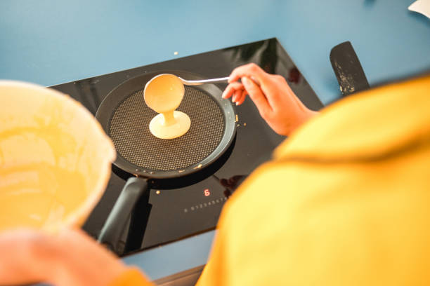 An unrecognizable woman making American pancakes for a family breakfast at home.