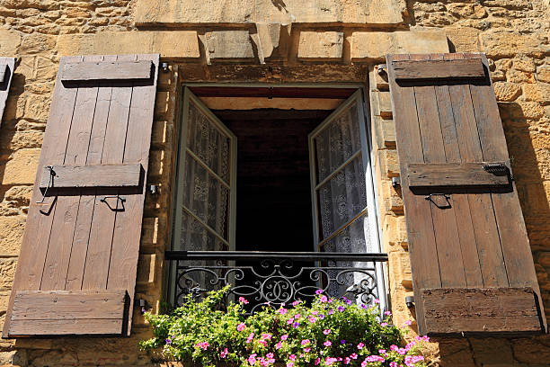 rustic wooden window on a stone wall at saint amand de coly , perigord noir in aquitaine, france