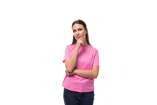 portrait of a young slim brunette woman in a pink basic t-shirt on a white background with copy space.