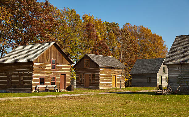 Rustic Village of Cabins With Autumn Trees Rustic Village of Cabins With Autumn Trees wagon wheel bench stock pictures, royalty-free photos & images