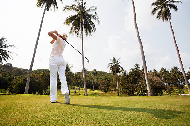 istock Rear view of young golfer woman taking a swing. 186849714