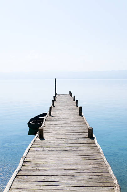 Wooden Jetty with Rowing Boat resting on one peaceful morning. Clear sky over the blue lake.See more images like this in: