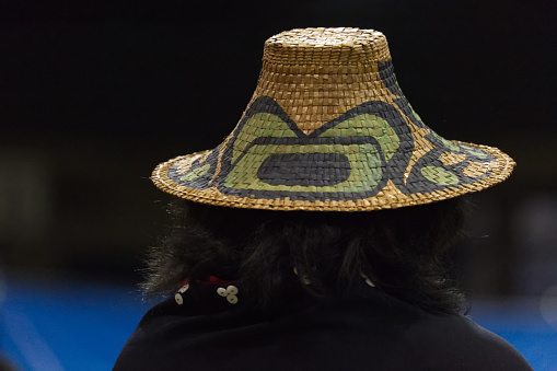 The Nisga'a Nation Hobiyee festival celebrated in Vancouver, Canada on 6 February 2015. The celebration commemorates the Nisga'a Nation's lunar new year. The Nisga'a gathering is powerful with the beating of drums, dance and beautifully intricate regalia. We see the back of an intricately woven and painted hat.