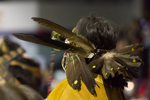 The Nisga'a Nation Hobiyee festival celebrated in Vancouver, Canada on 6 February 2015. The celebration commemorates the Nisga'a Nation's lunar new year. The Nisga'a gathering is powerful with the beating of drums, dance and beautifully intricate regalia. Headband with many feathers, dotted with yellow.