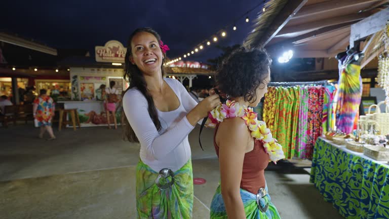 Woman puts lei necklace on friend