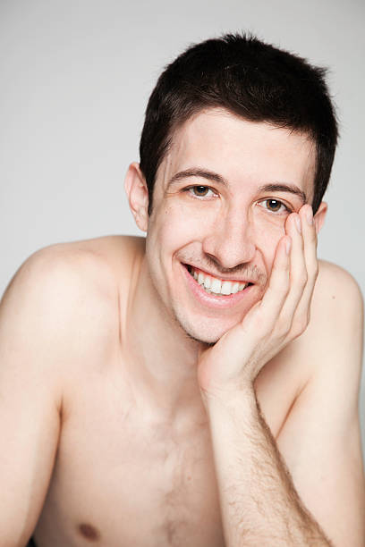 istock Young shirtless man smiling with head resting in hand 186850988